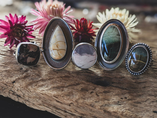 5 jasper rings sitting side by side, showcasing a variety of stone colors and ring designs