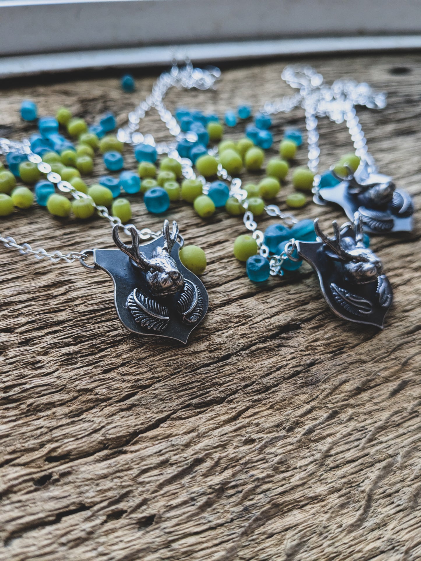 jackalope mount necklace made of sterling silver featuring fern fronds below the jackalope