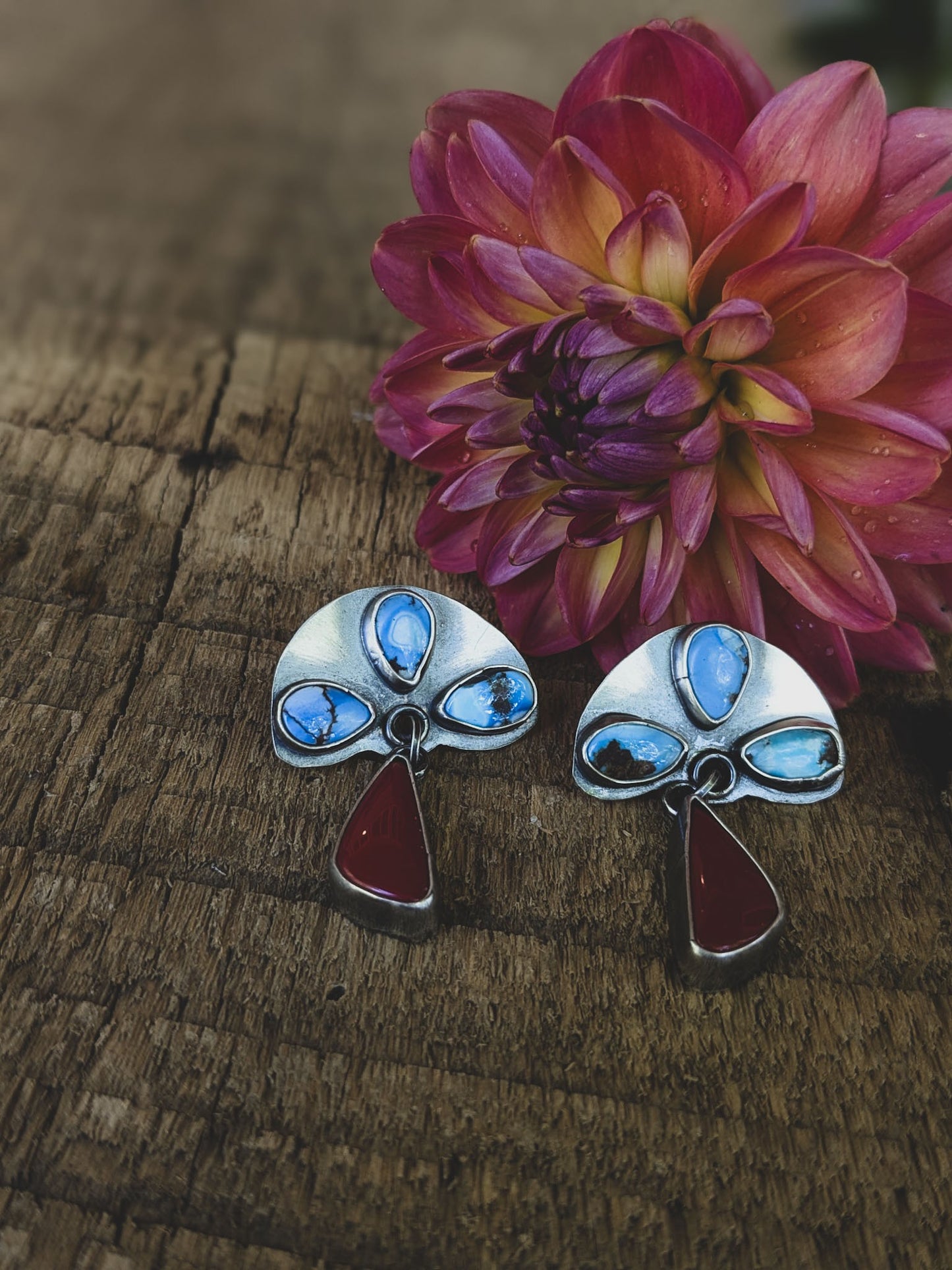 turquoise stones are set in sterling silver above dangles made of deep red carnelian